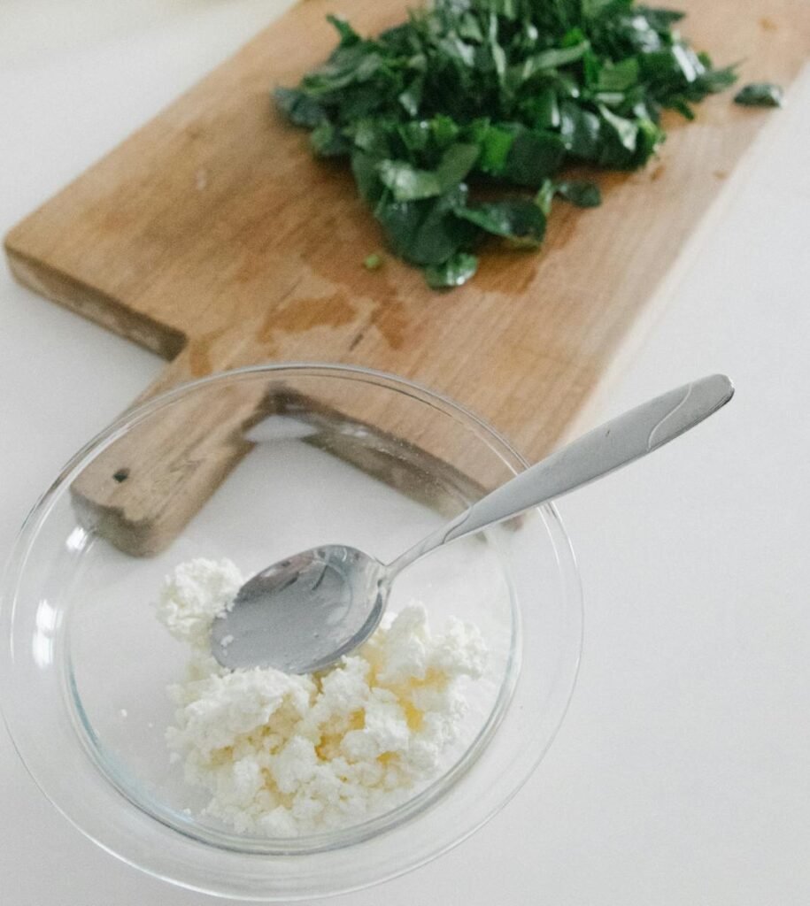 Close-up of feta cheese with fresh herbs on a cutting board, ideal for food preparation themes.