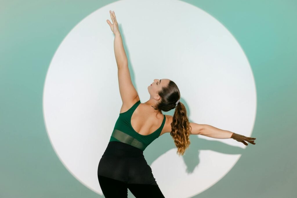 A dancer in motion poses gracefully against a lit circular backdrop, showcasing elegance and balance.