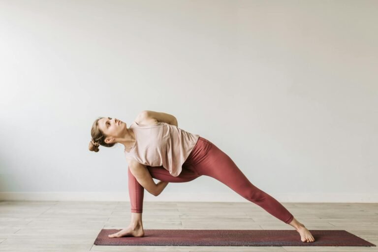 A woman practicing a yoga pose indoors on a mat, showcasing flexibility and wellness.