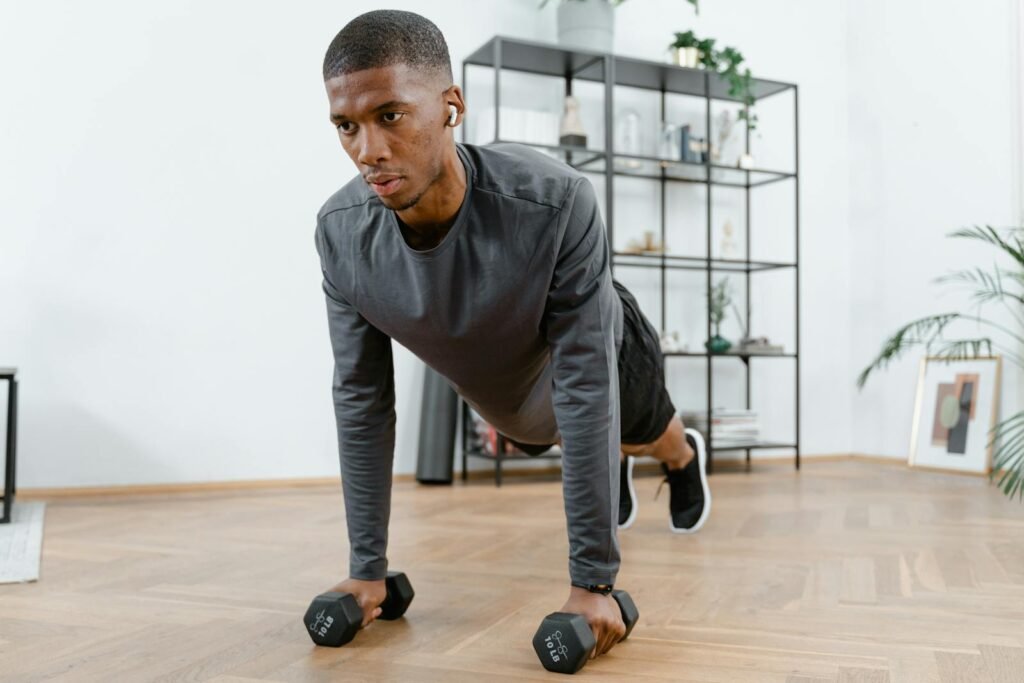 Man performing push-up exercises with dumbbells indoors. Fitness and healthy lifestyle concept.