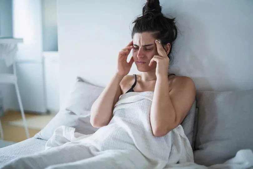 Jeune femme ayant un mal de tête et tenant sa tête dans ses mains.
